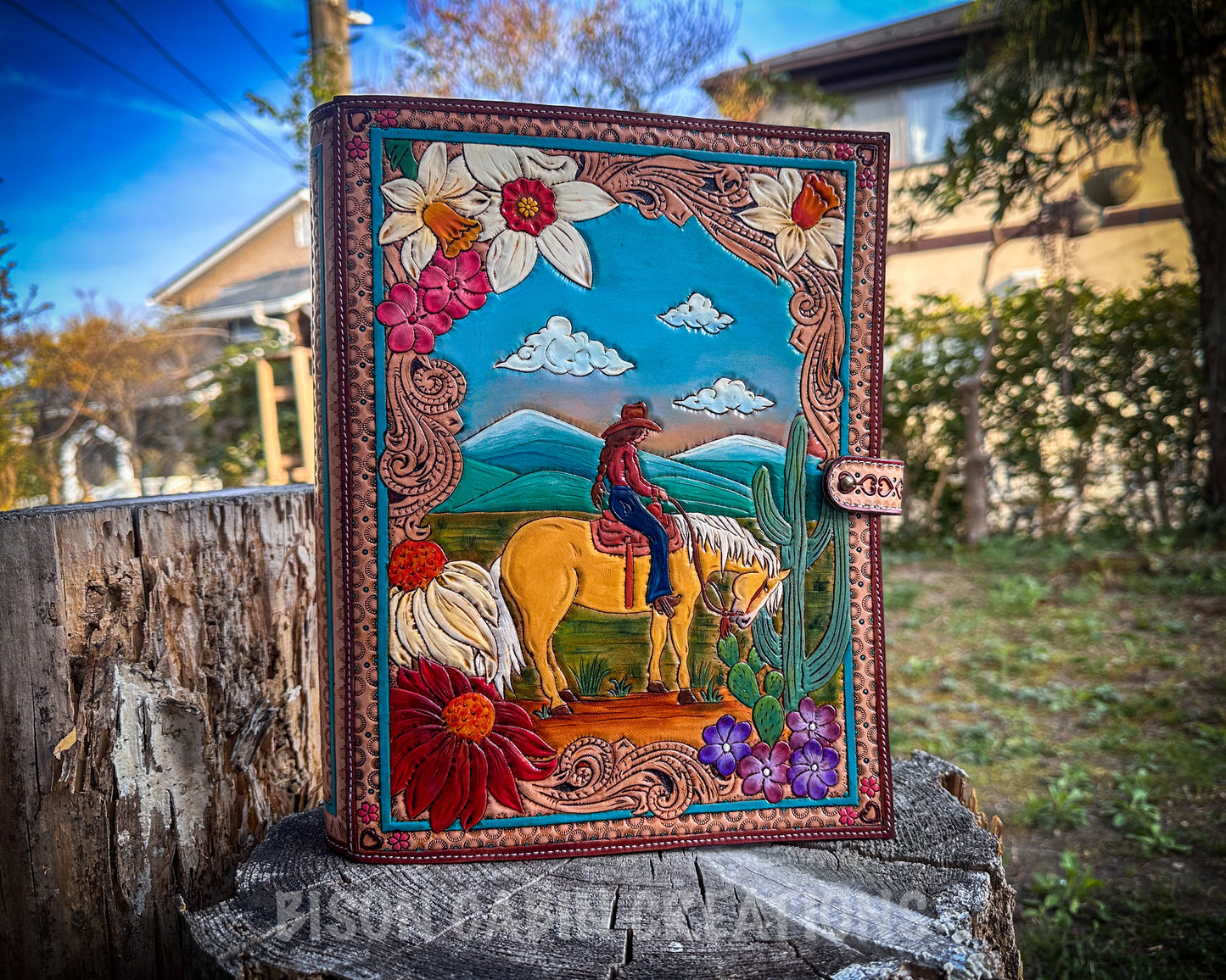 Handcrafted leather portfolio featuring cowgirl on horseback, desert scene with cactus and flowers, western tooled notebook cover