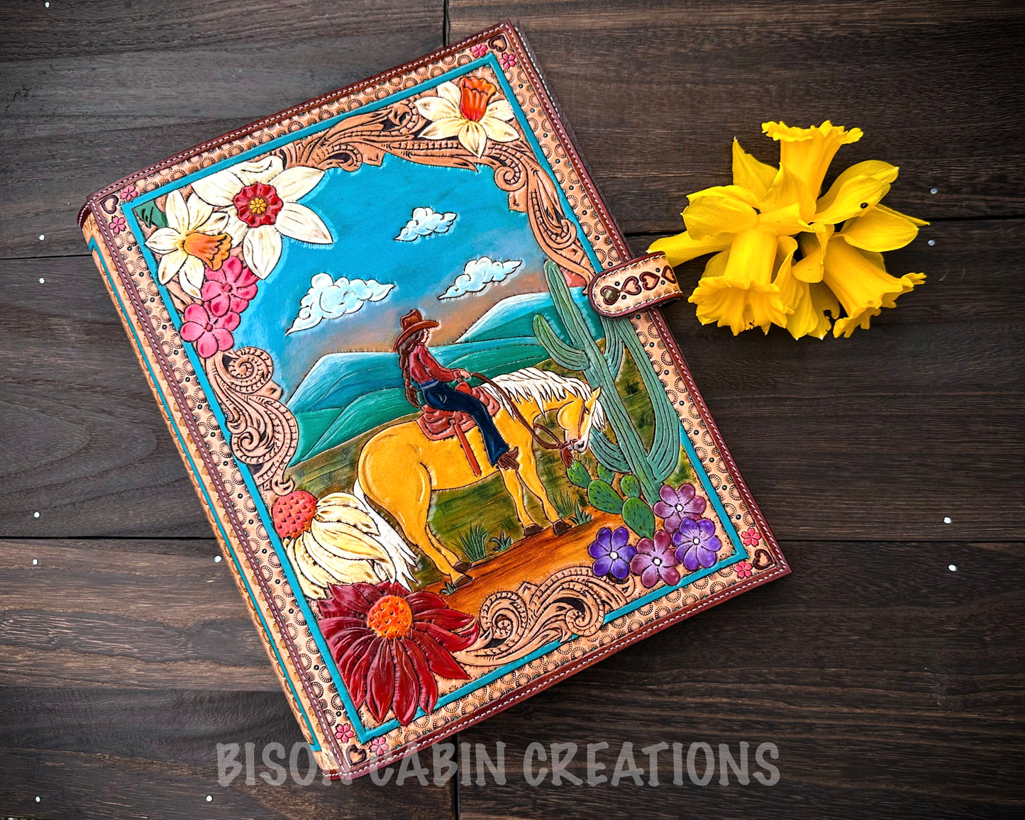 Hand tooled leather padfolio with colorful Western cowgirl riding horse design, floral details, cactus and desert landscape, rustic personalized notebook cover