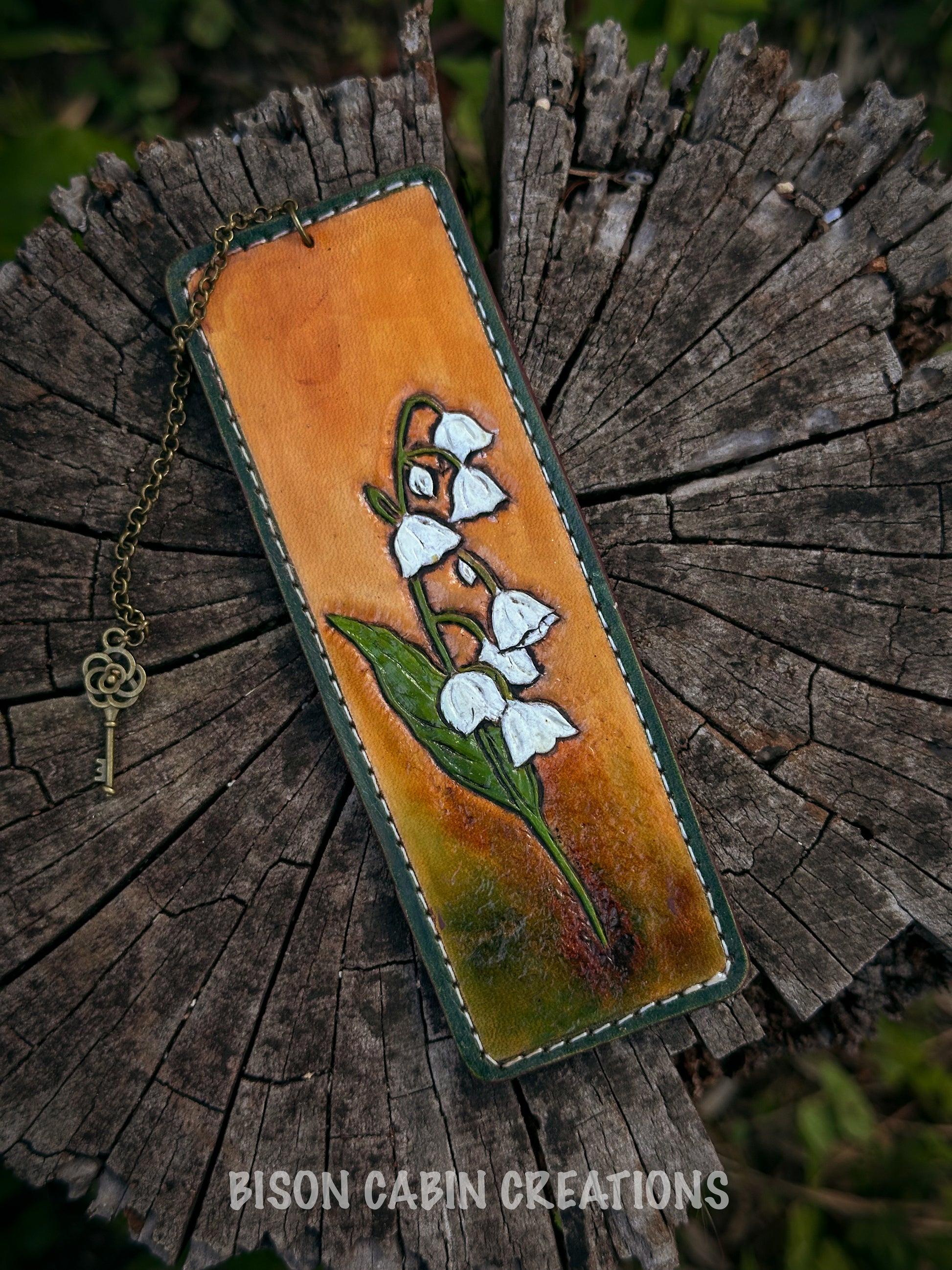 Handmade leather bookmark with floral design, Lilly of the Valley featuring 'Bison Cabin Creations' branding.