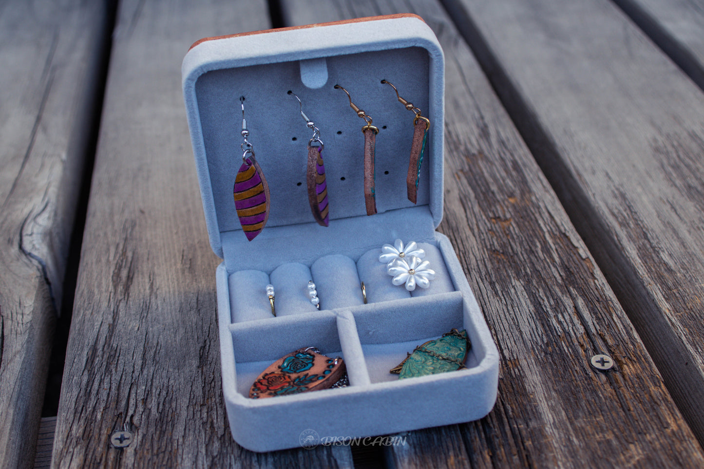 Open view of handmade leather jewelry box interior with soft lining, compartments for rings, earrings, and accessories, and rustic handcrafted finish