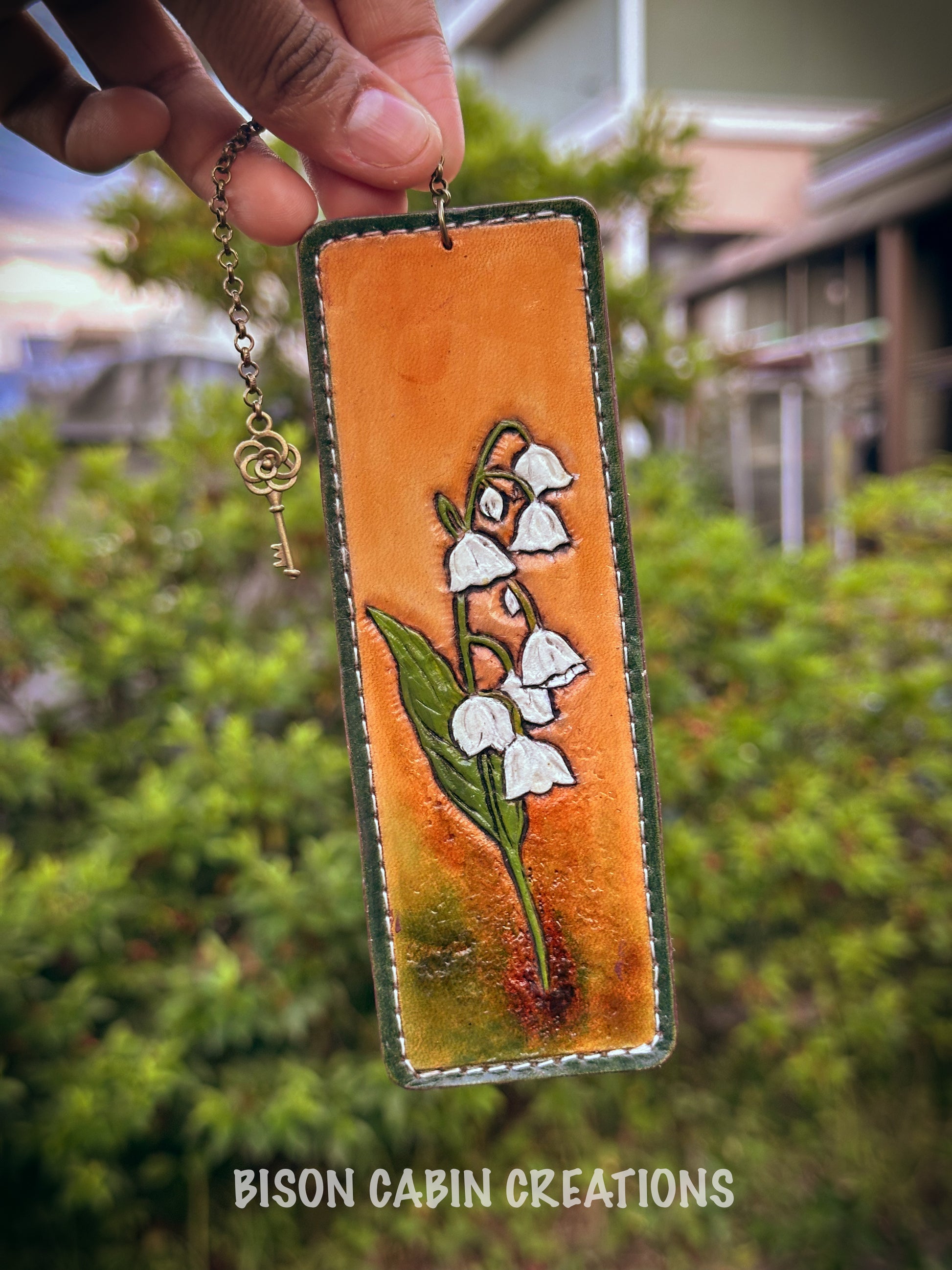 Handmade leather bookmark with Lilly of the Valley featuring .'Bison Cabin Creations' branding.