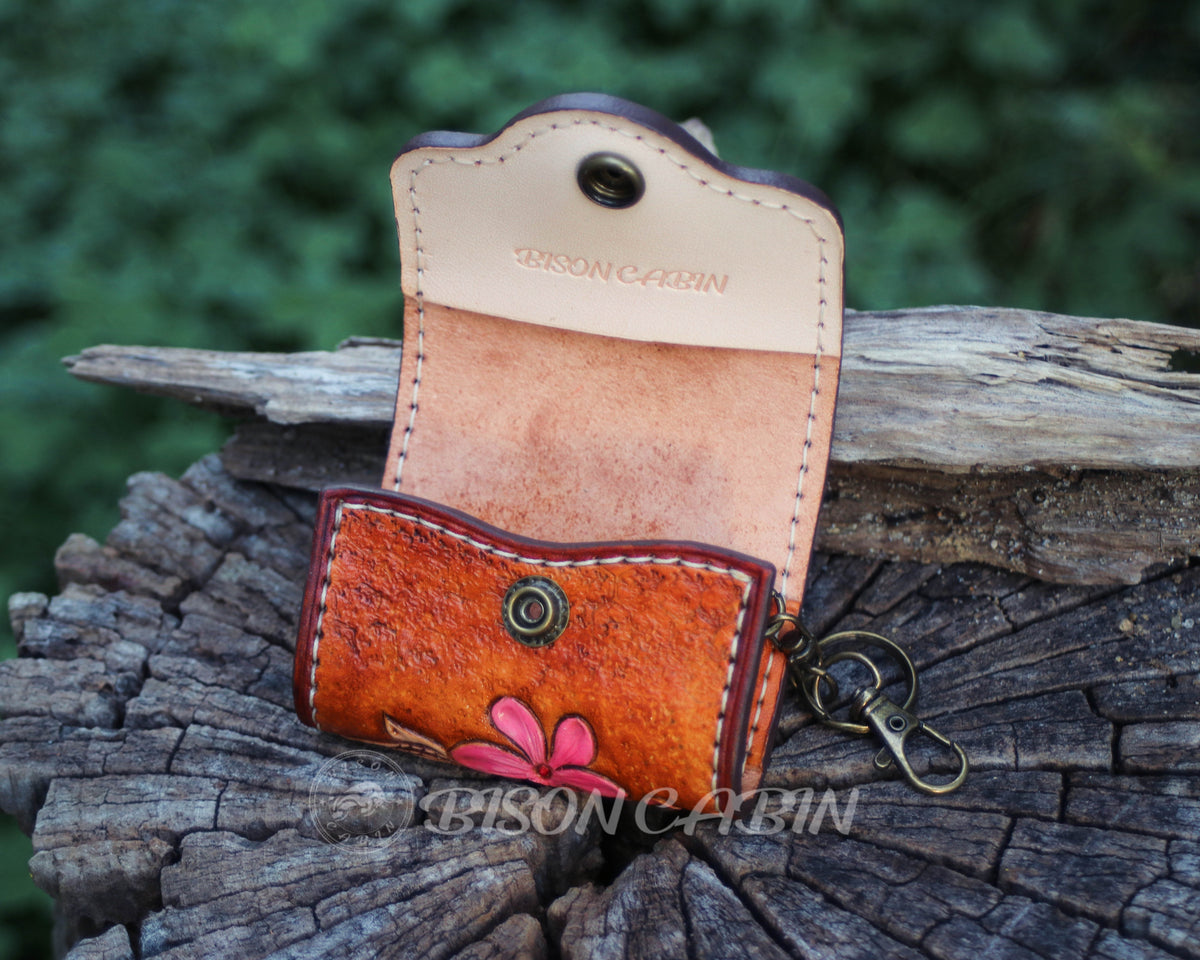 Handcrafted tooled  leather AirPods cases featuring embossed flowers, and antique-style metal hardware.