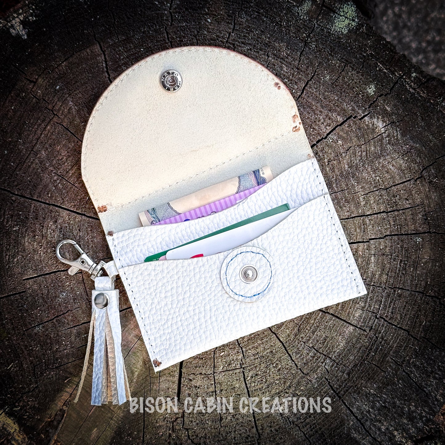 Custom tooled leather wallet featuring a painted cowgirl riding a horse surrounded by flowers, with white leather tassel keychain attached, styled outdoors.two card pockets 