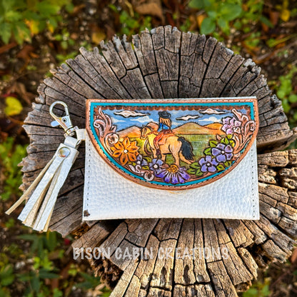 Premium handcrafted Tochigi leather wallet with vibrant western artwork, floral carving, and white pebble leather base, photographed on wood stump.