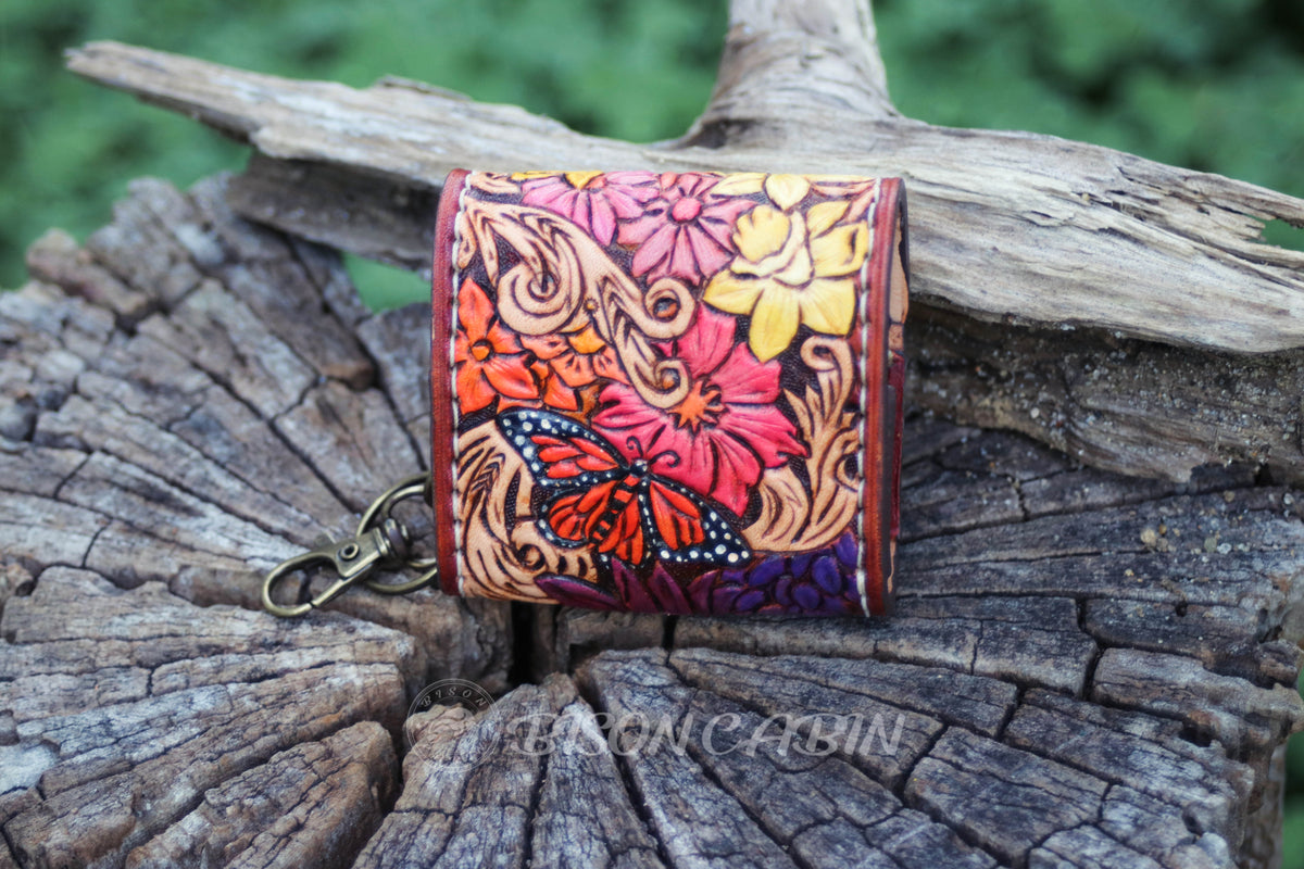 Handmade wildflower leather AirPods cases featuring embossed flowers, western scrolling with monarch butterfly  and antique-style metal hardware.
