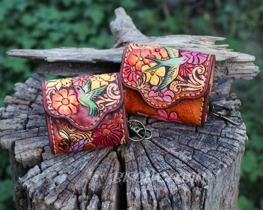 Handcrafted tooled leather AirPods case featuring colorful flowers and a hummingbird and Songbirds design.