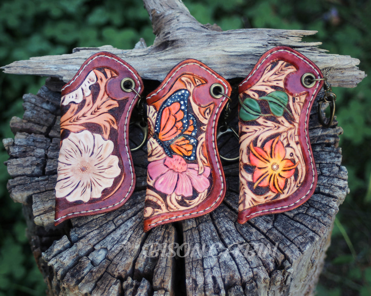Hand-tooled floral leather lighter case with a white flower and Western scroll carving, handmade cowhide leather keychain holder.