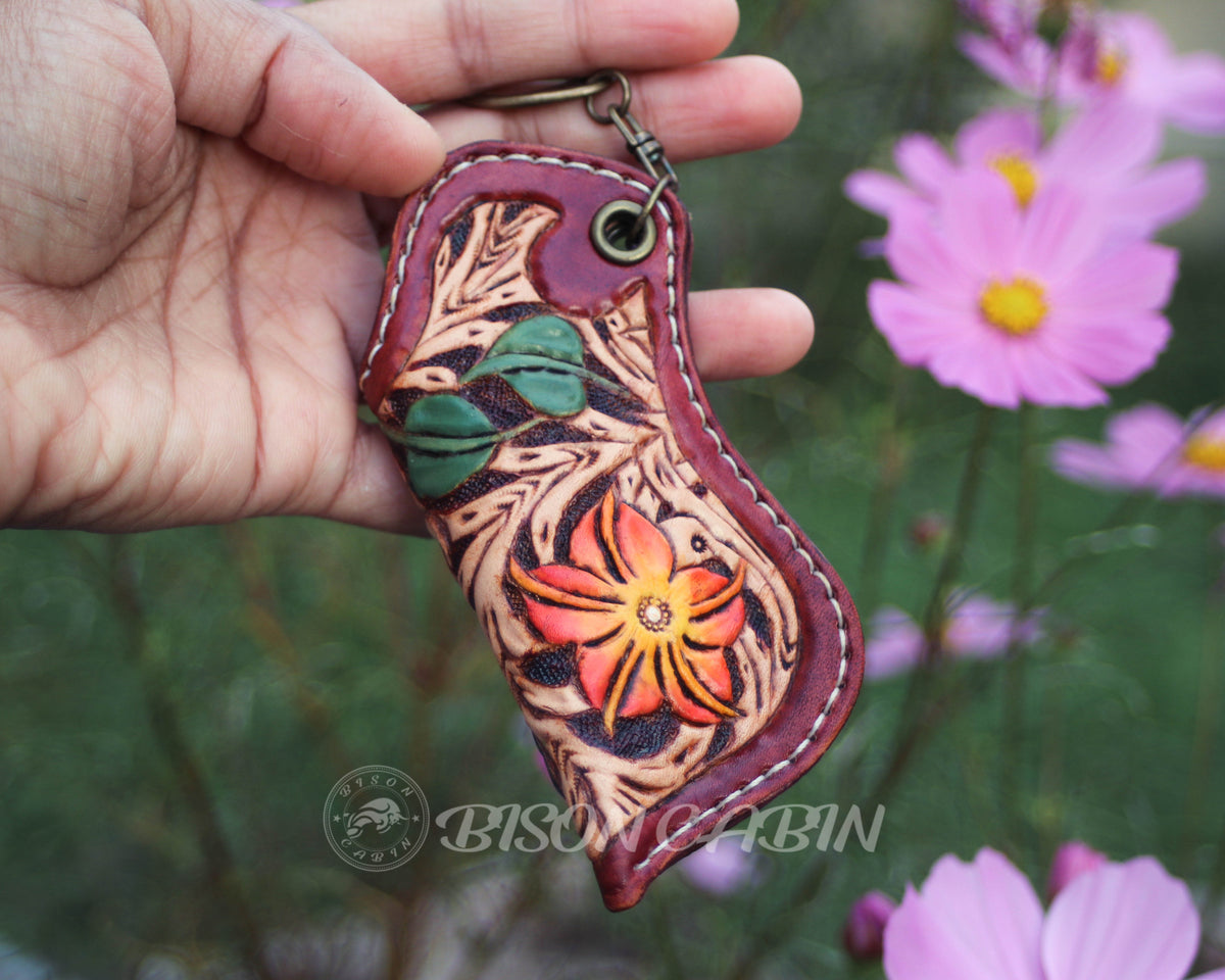 Handmade floral leather lighter case featuring an orange flower, green leaves, and intricate Western scroll tooling on genuine cowhide leather.