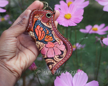 Handmade butterfly leather lighter case featuring a colorful orange and blue monarch butterfly, pink flower, and hand-tooled Western scroll design.