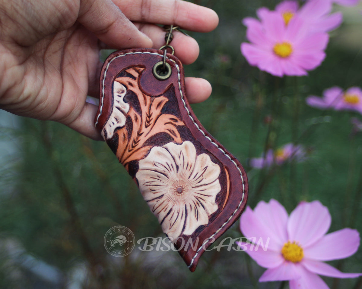 Hand-tooled floral leather lighter case featuring a large white flower, Western scroll carving, and hand-painted details on genuine cowhide leather.