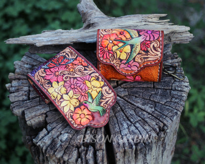 Wildflower-themed leather AirPods case with intricate tooling, bright floral accents, and rustic brown leather.