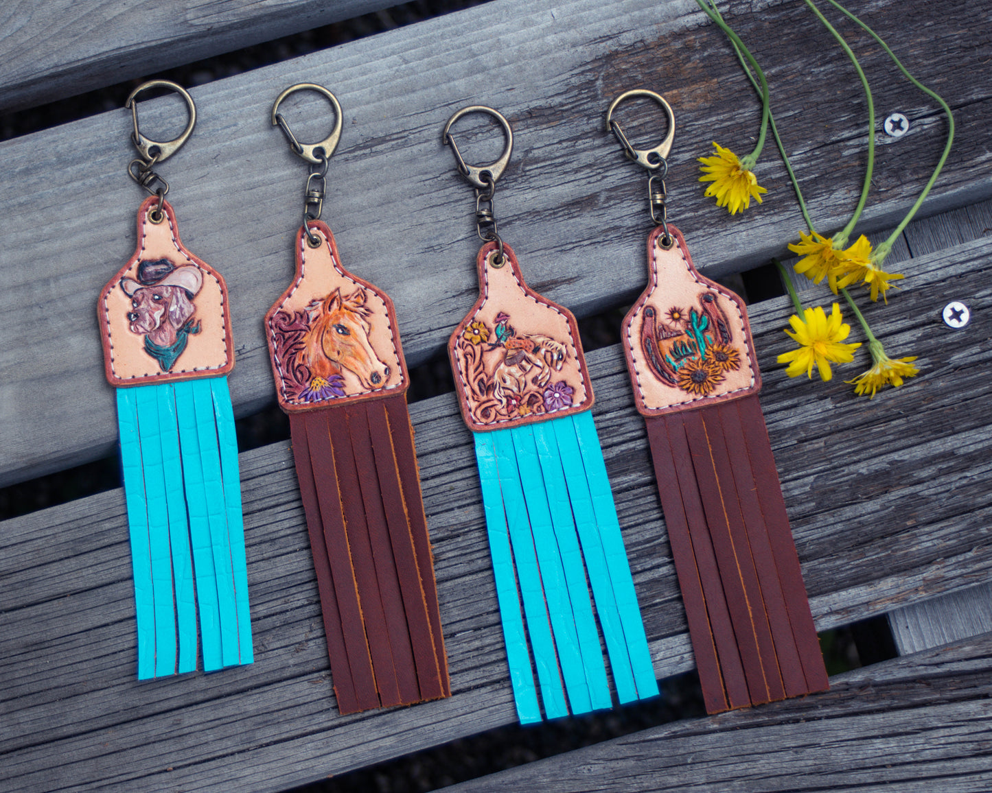 Collection of handcrafted, tooled leather keychains featuring horse, cow, dog, and horseshoe designs with rustic Western detailing and charm accessories